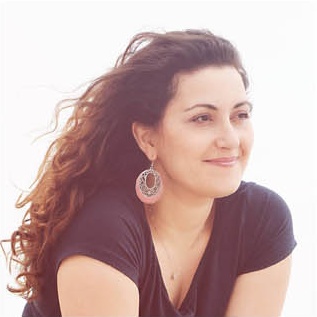 Ritratto di Ester Menniti, sorridente, con i capelli mossi dal vento